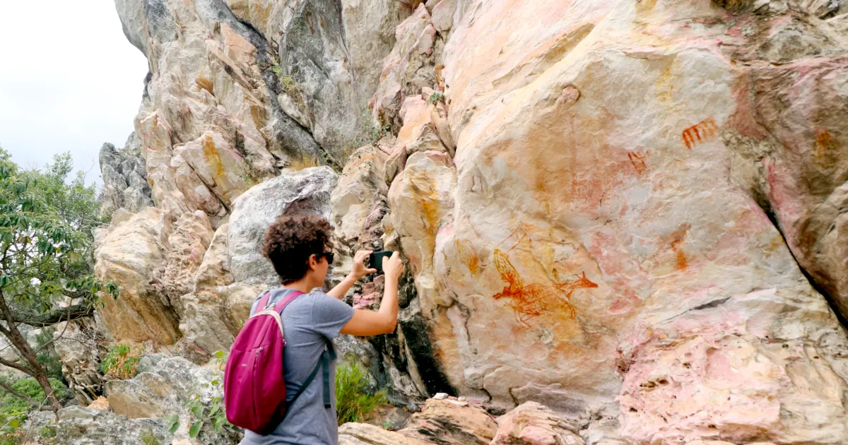 Foto da arqueóloga Marina Gomide fotografando pintura rupestre na Lapa Vau da Lagoa.